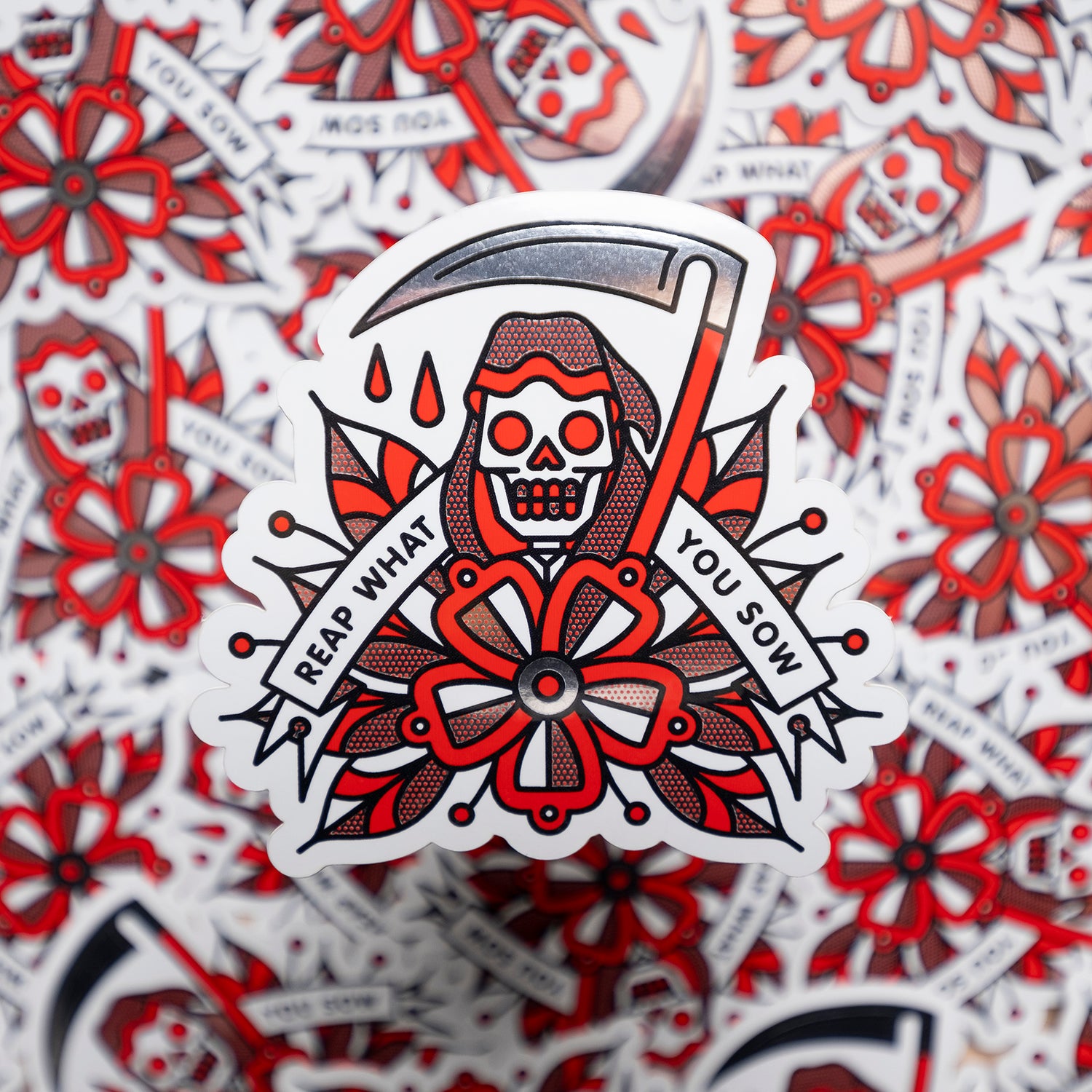 A 3.3x3.2" metallic vinyl art sticker of a grim reaper holding a scythe behind a large flower. A banner reads: Reap what you sow. Drawn in a flash tattoo and pop art fusion style in a red, white and black color palette by the artist, Red Halftone.